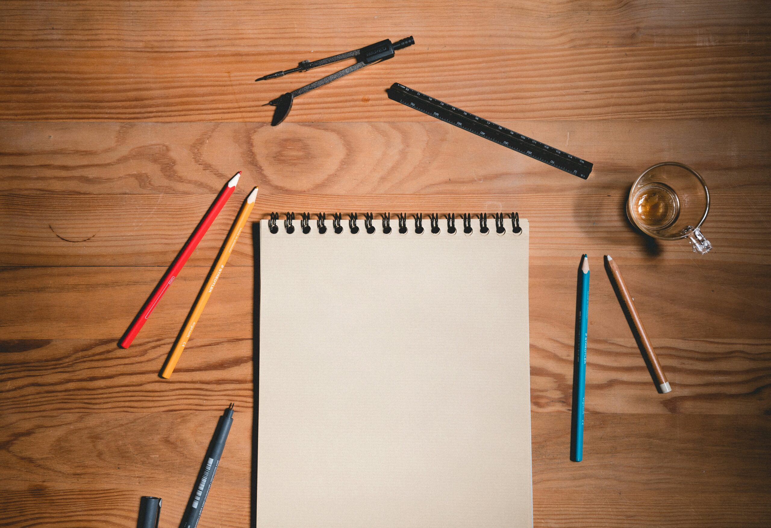 Empty pad and colors pencils on a wooden desk